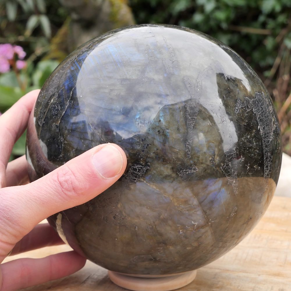 Bijzonder grote labradoriet bol met diameter van 18cm! Achterzijde met hand