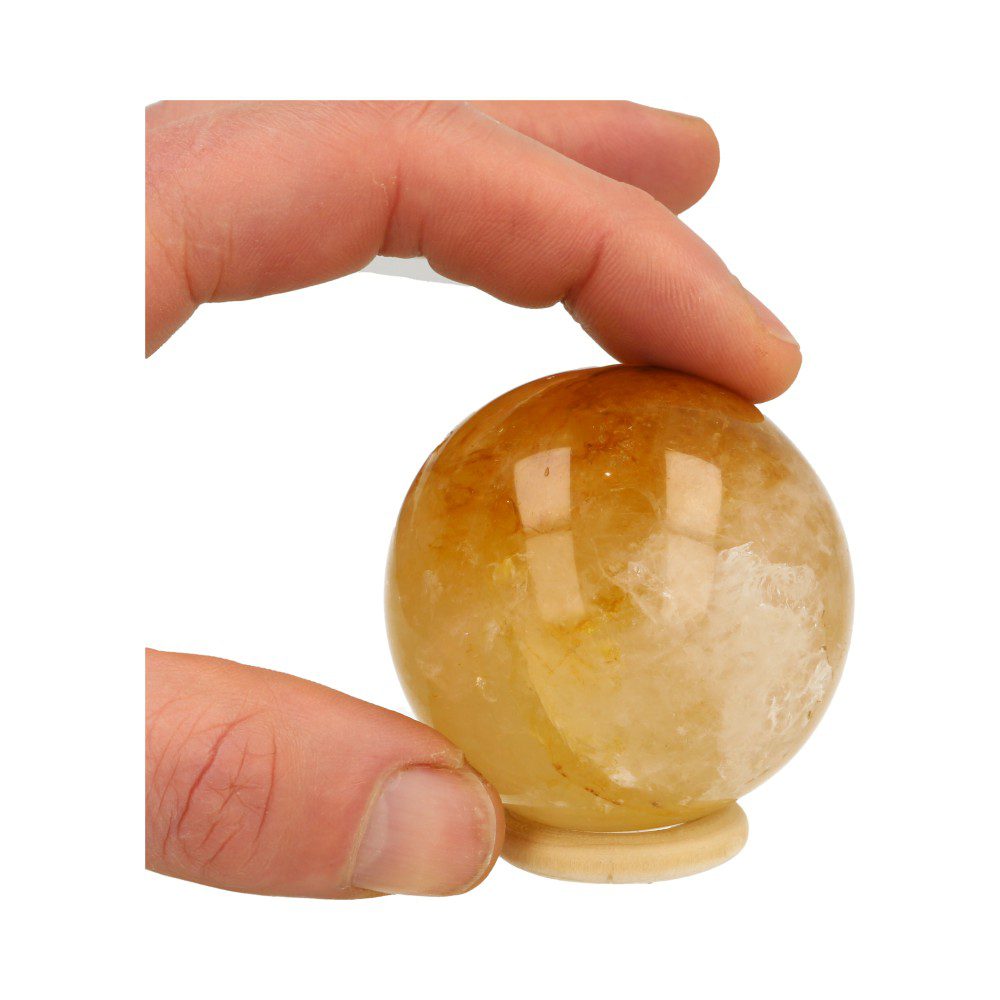 Overzichtsfoto in hand van Fijne lichtgele golden healer bol met diameter van ruim 56mm op houten ring