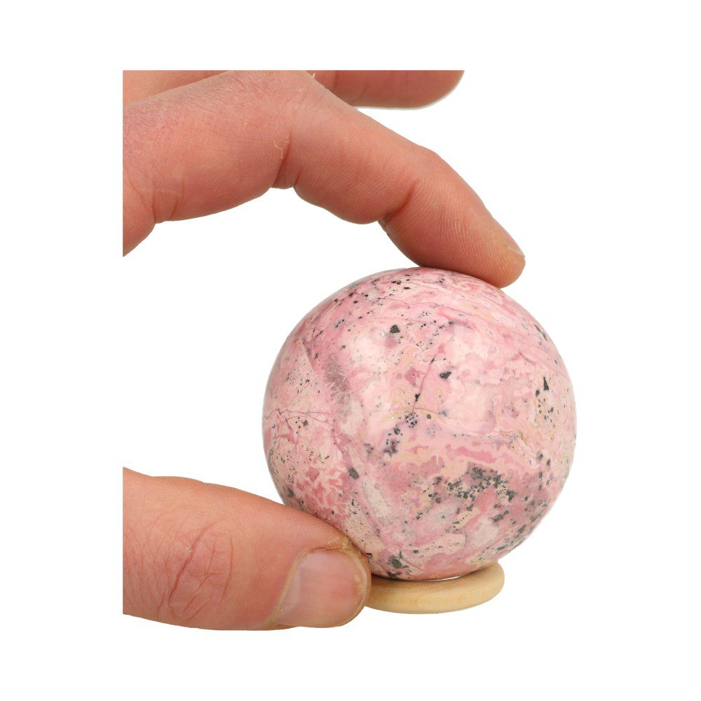 Prachtige A-kwaliteit roze rhodoniet bol uit Peru met diameter van 59mm op houten ring, in hand