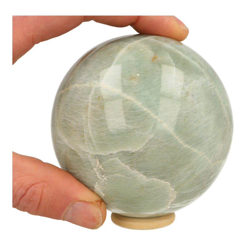 Overzicht in hand van fraaie groene maansteen bol met lichte kleur en mooie glans met diameter van 86mm en houten ring